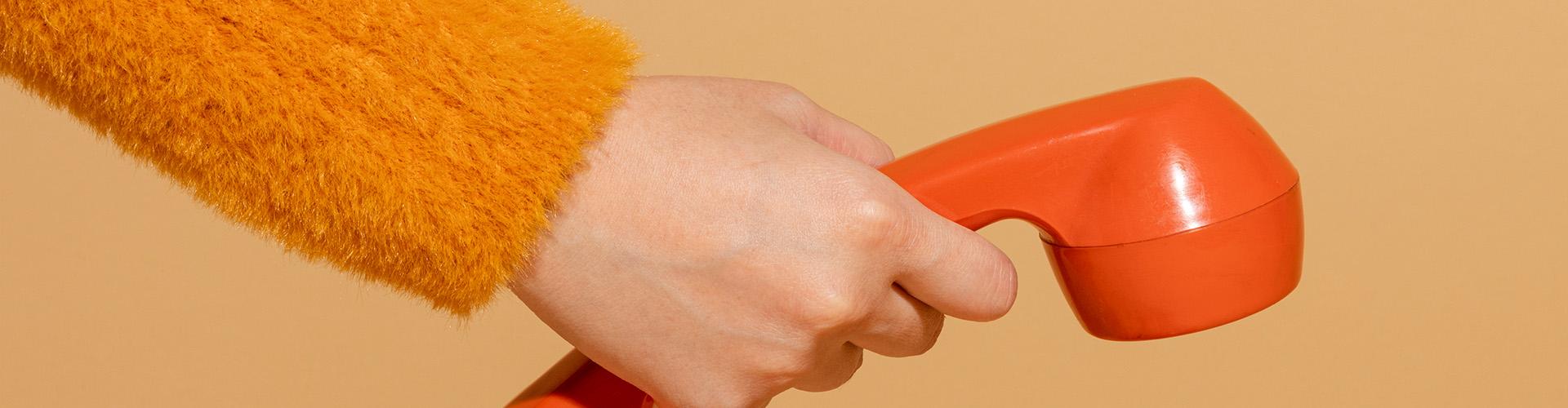 Une main tendue avec un vieux combiné téléphonique pour contacter les experts de Citéfid.